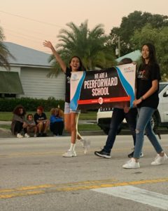 Two Peer Leaders hold up poster that states "We are a PeerForward school"