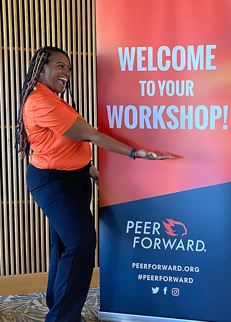 peerforward staff smiles at welcome to your workshop sign