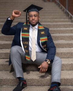 Young man in graduation garb doing a power fist