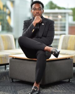 Young man in suit posing for camera with his hand on his chin.