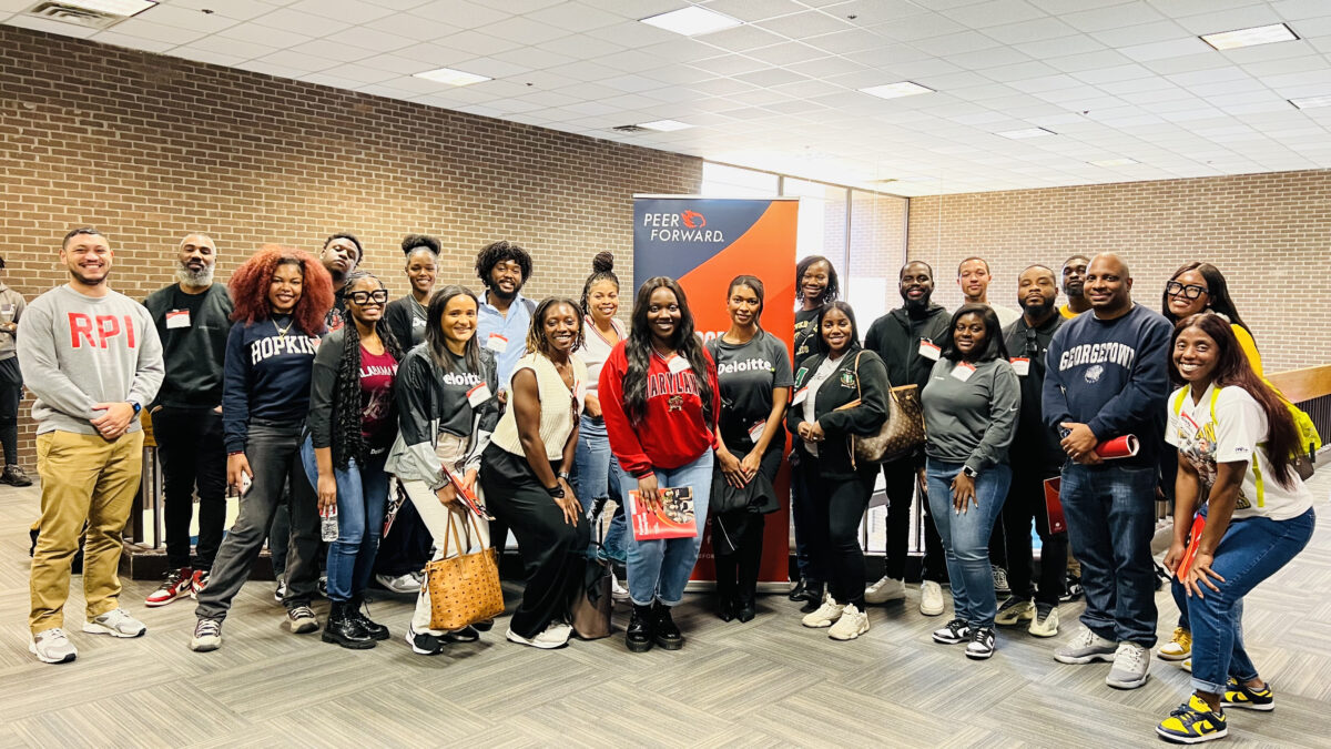 Deloitte volunteers post in front of a PeerForward sign at Prince George's Community College