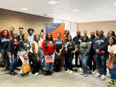 Deloitte volunteers post in front of a PeerForward sign at Prince George's Community College