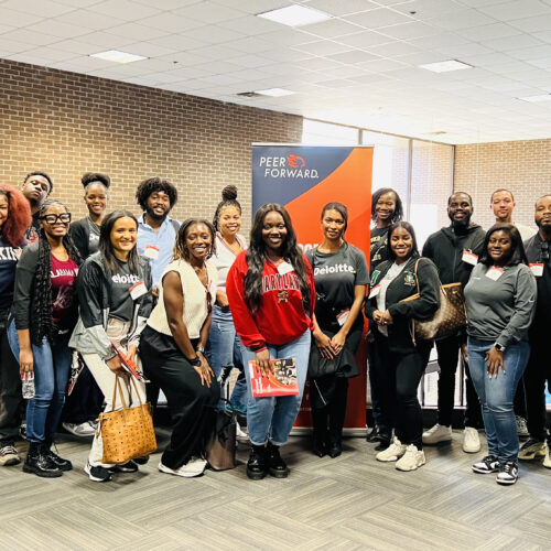 Deloitte volunteers post in front of a PeerForward sign at Prince George's Community College